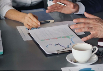 Photo of a business meeting, with focus on the table, with a chart and a coffee cup